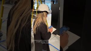 Photo d'une employée utilisant un smartphone dans un environnement de bureau moderne.