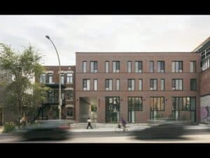 Bâtiment de bureaux moderne avec façade en briques, grandes fenêtres et espace extérieur urbain.