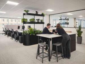 Espace de coworking avec deux personnes discutant près d'une table haute.