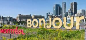 Signes géants 'BONJOUR' et 'MONTRÉAL' avec skyline de Montréal en arrière-plan.