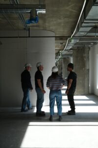 Groupe de quatre personnes avec casques de sécurité dans un bâtiment en construction.
