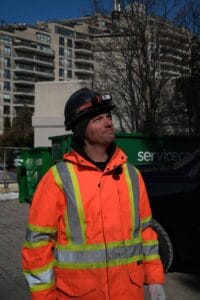 Technicien en sécurité avec casque et veste haute visibilité en milieu urbain.