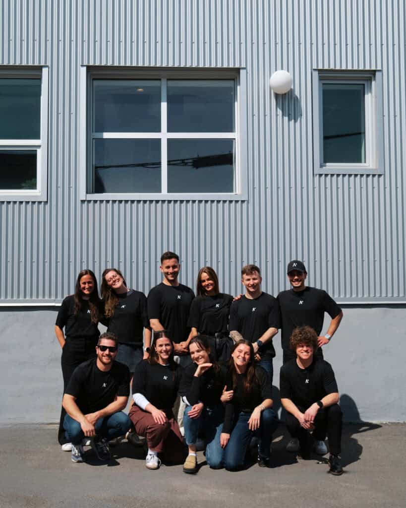 Groupe de jeunes professionnels devant un bâtiment moderne en extérieur.