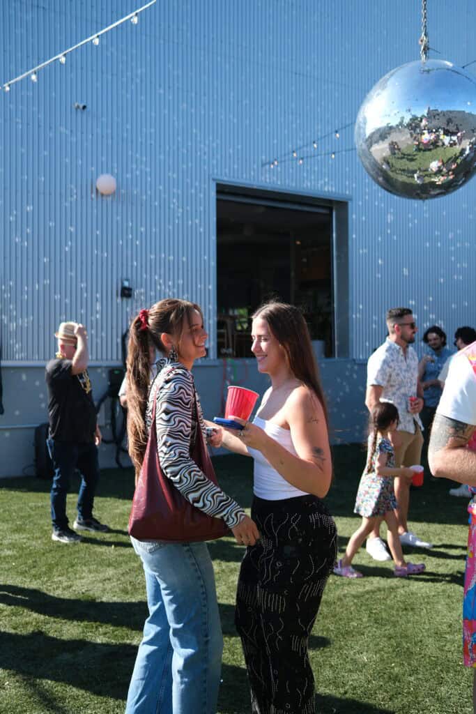 Deux femmes discutent lors d'une fête en plein air avec un décor festif.