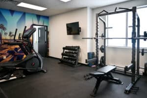 Salle de sport équipée avec tapis de course, haltères et machine de musculation.