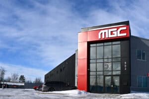 Façade du bâtiment MGC avec logo visible et parking extérieur.