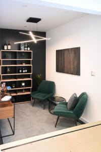 Salon moderne avec fauteuils verts, étagère noire et décoration contemporaine.