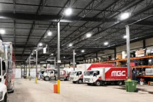 Camion MGC dans un entrepôt industriel avec véhicules de livraison.